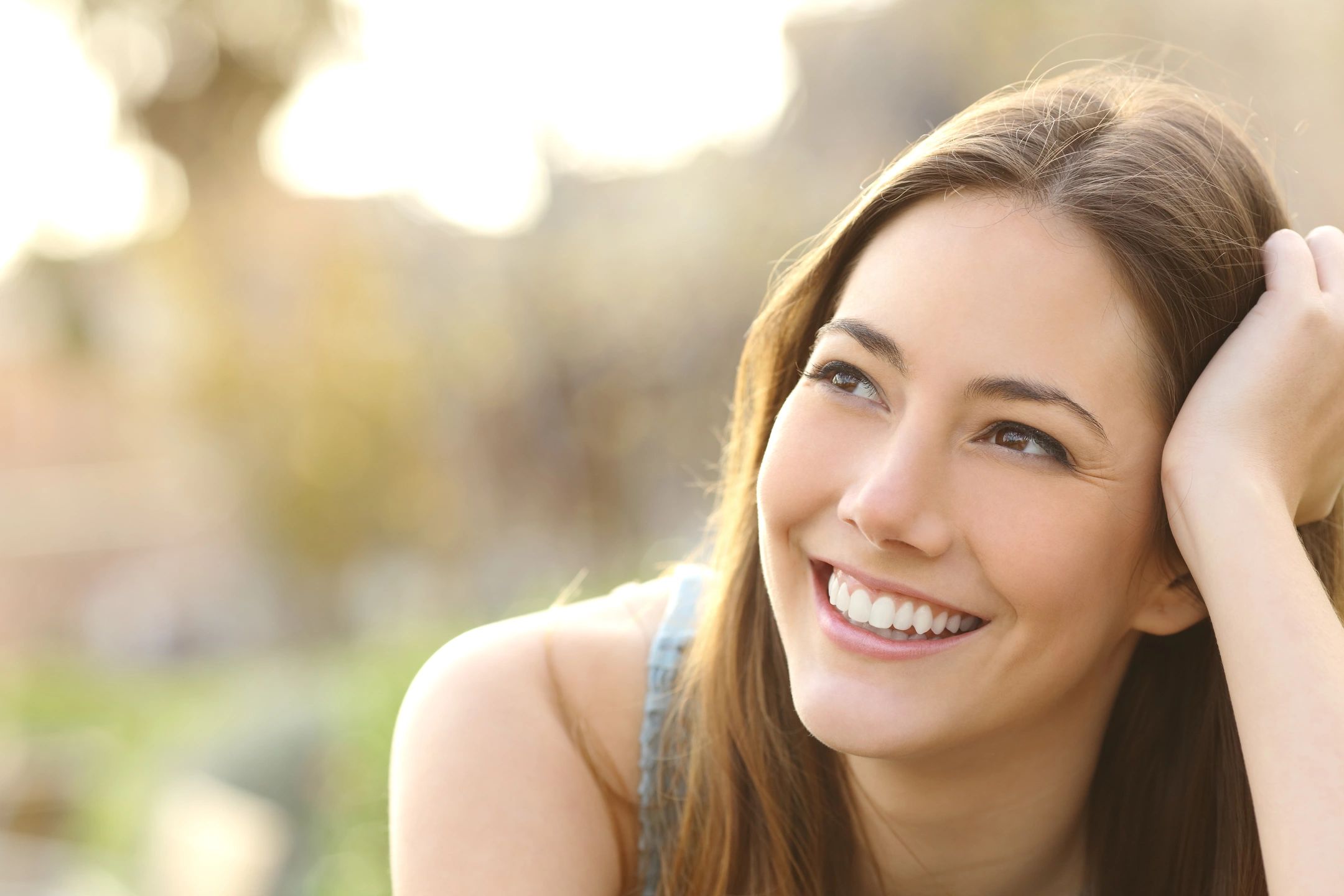 A woman smiling with her teeth looking to the side.