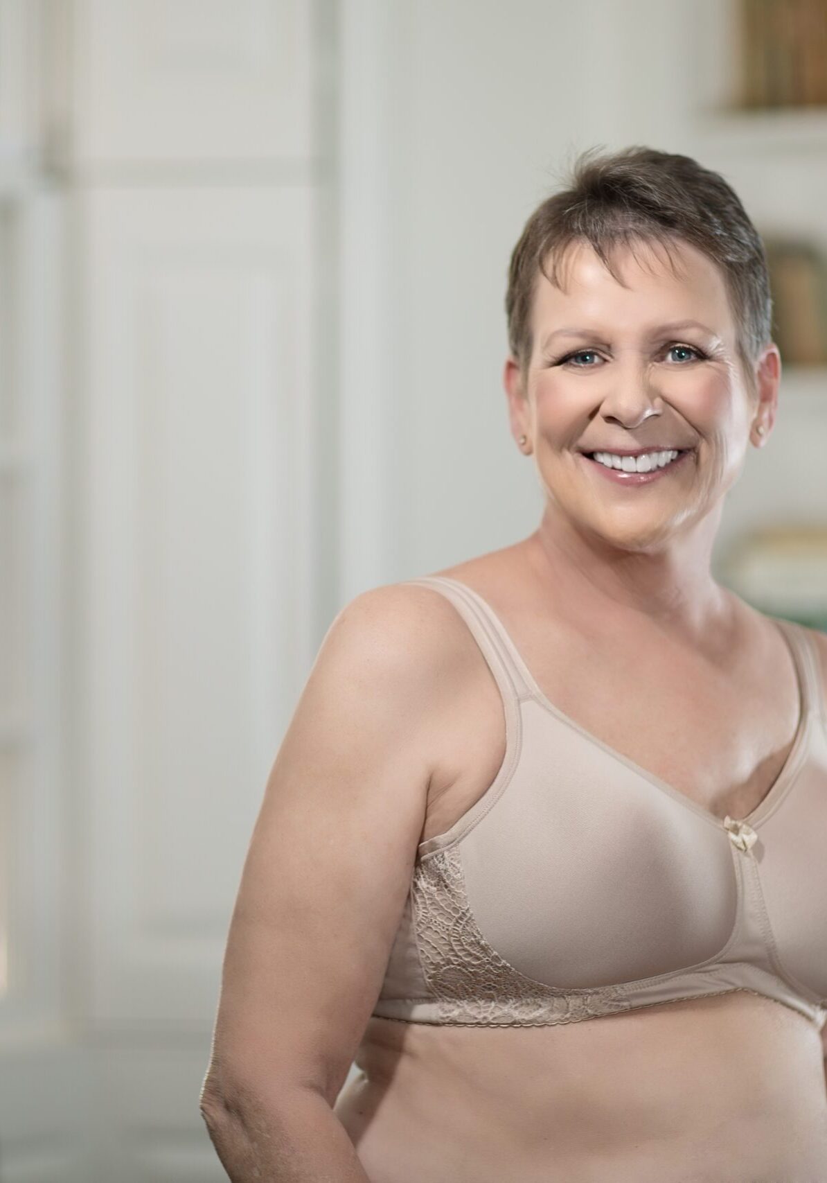 A woman in beige bra standing next to a window.