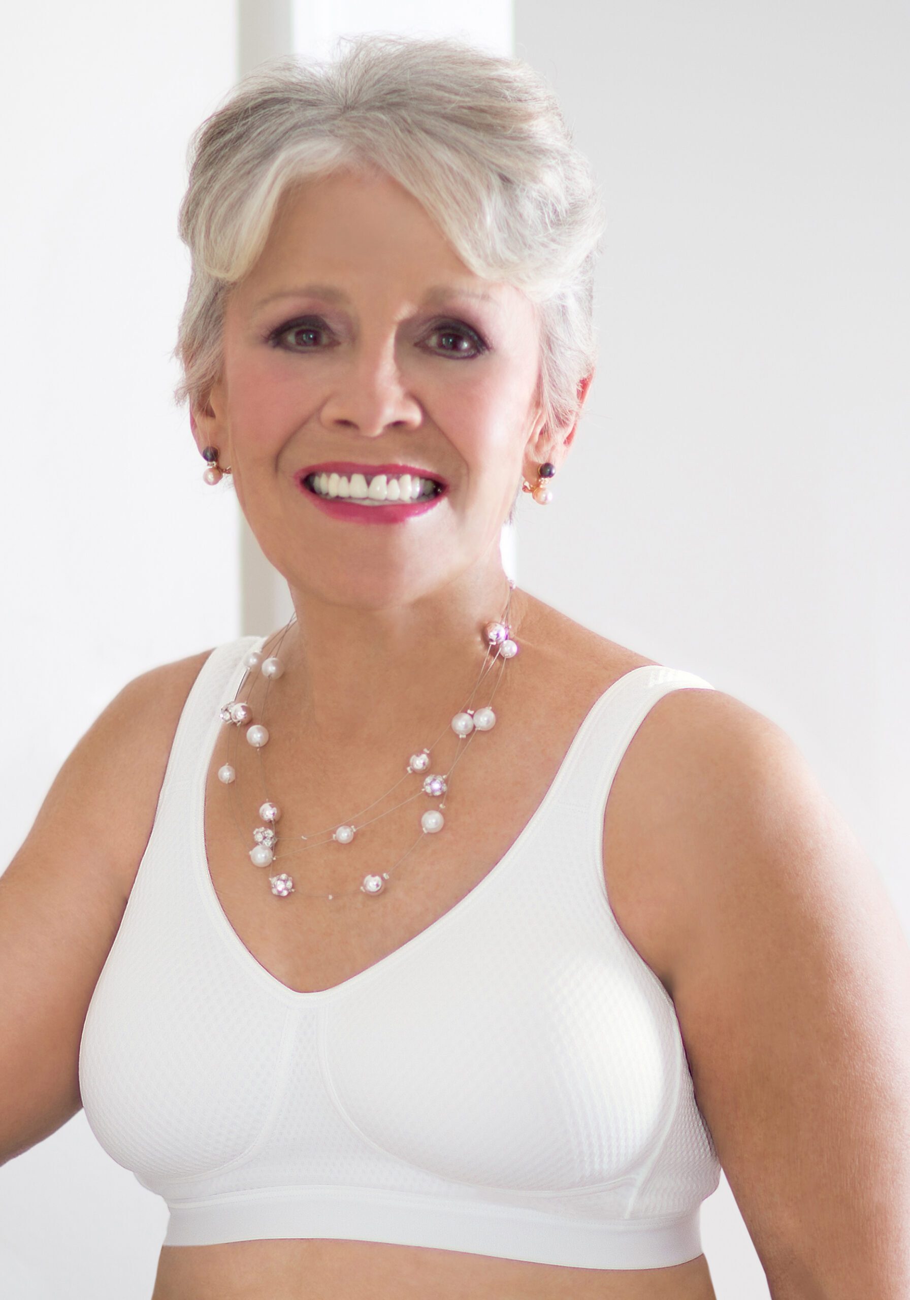 A woman in white dress with pearls around her neck.