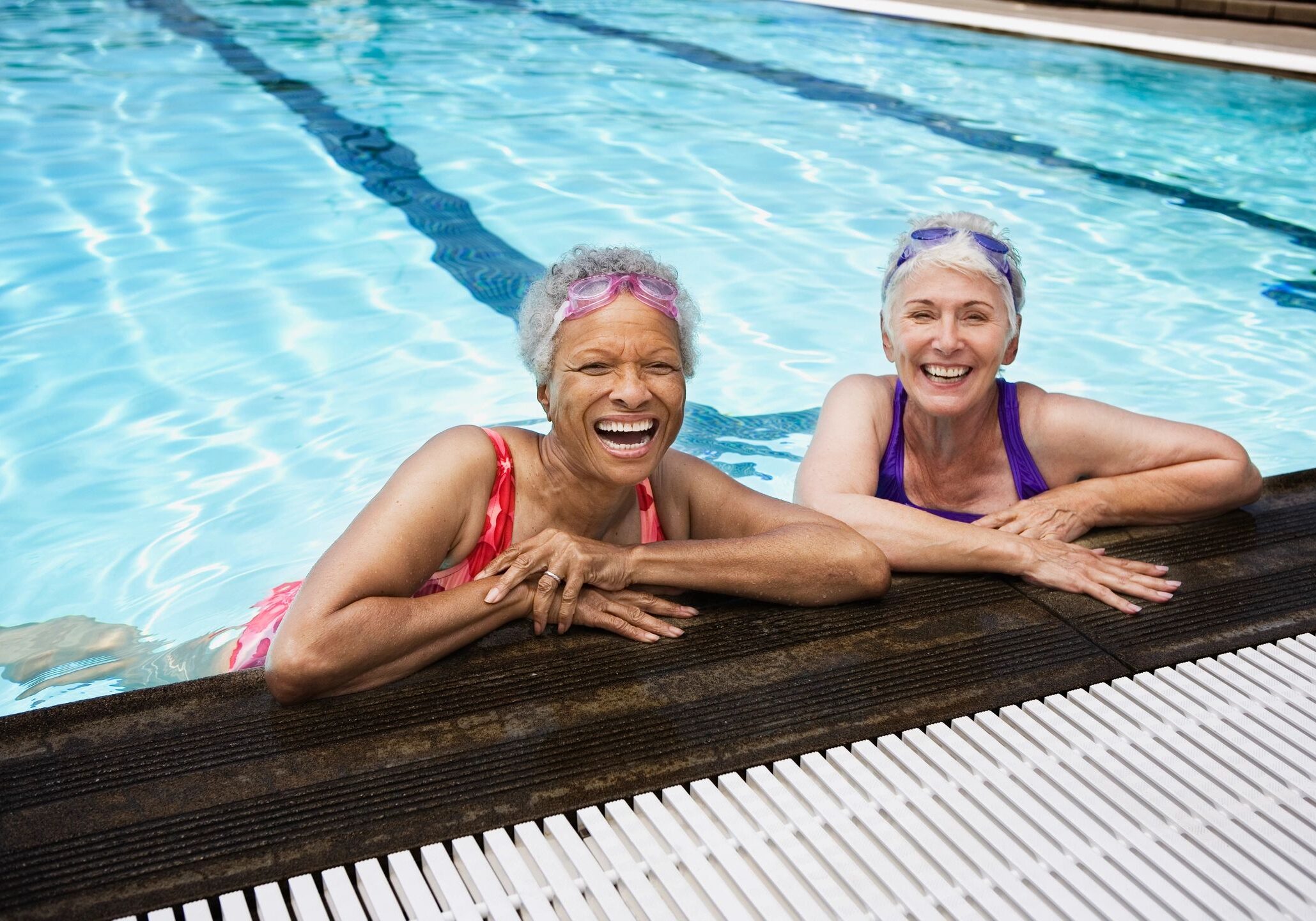 Two women in swim caps and a pool